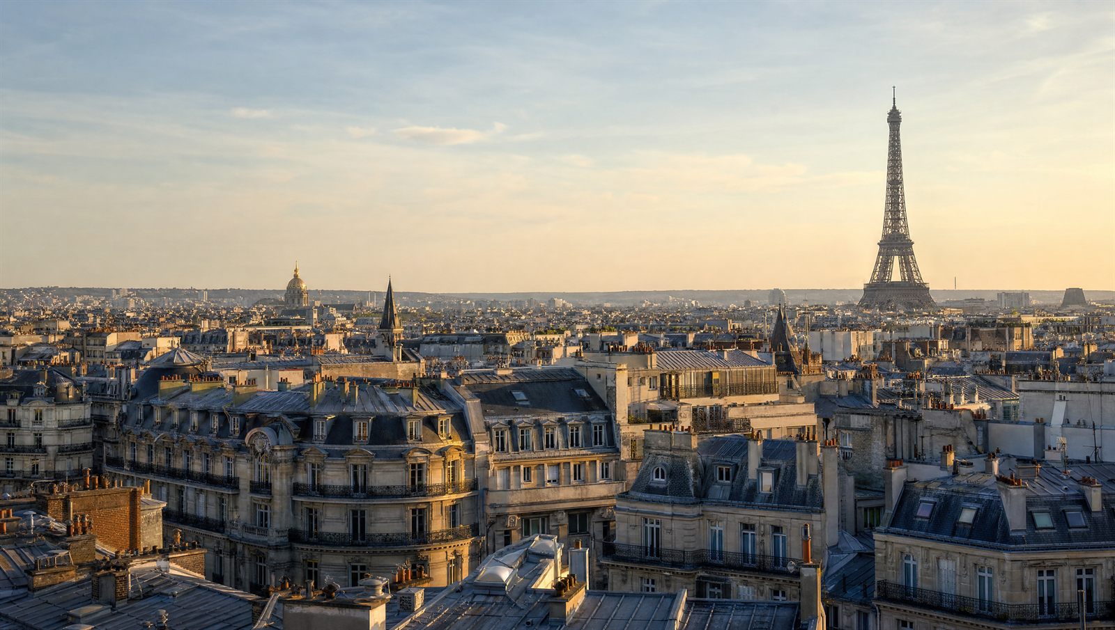 Toits haussmanniens de Paris au coucher du soleil avec la tour Eiffel a l'horizon